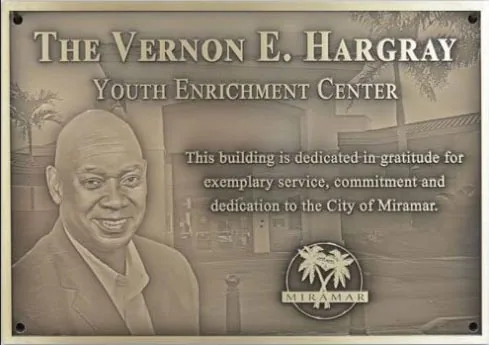 A bronze family business dedication plaque featuring a photo of the building in the background.