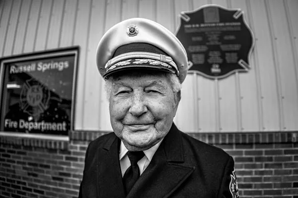 A fire chief standing in front of the new fire station dedication plaque.