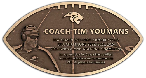 A football-shaped bronze recognition plaque honoring a head football coach, with a bas-relief portrait, team logo, and engraved coaching record.