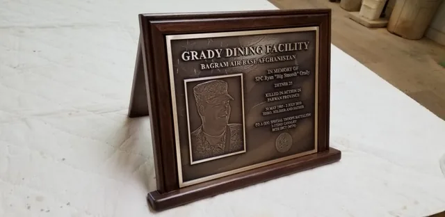 Smaller replica of the Grady Dining Facility memorial plaque in a wooden desk stand