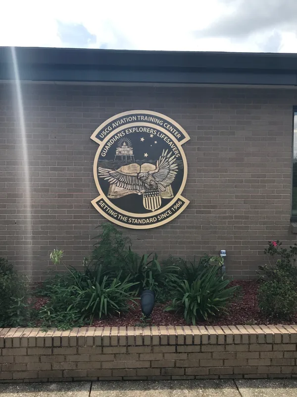 Large custom-shaped bronze emblem for the USCG Aviation Training Center mounted on brick